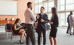 Three business people have a standing discussion