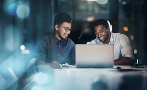 Two colleagues review the laptop for their CPQ software