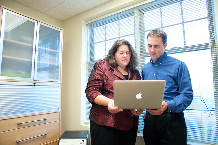 Two business people reviewing a MacBook to focus on a market