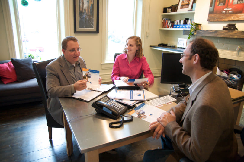 A group of business people sit down for a meeting at a desk