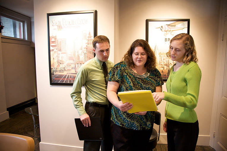 The professional growth strategies team meeting review documents while standing