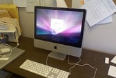 A Mac monitor sitting on a desk shows a purple screen
