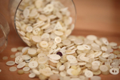 A large container full of buttons is tipped over, spilling its contents over the table