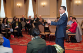 A company leader stands in front of an open floor to make an announcement