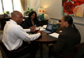 A business owner CEO, COO, and team member have a discussion around a table