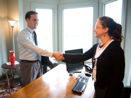 Two business people shake hands before sitting down for a meeting