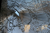 A hole is shown in a small sheet of glass where the remaining is fractured and broken