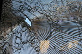A hole is shown in a small sheet of glass where the remaining is fractured and broken