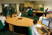 A large boardroom with workers surrounding a wooden table