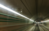 Lights show along the side wall of an empty train tunnel