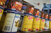 A side-angle photo of a grocery shelf showing different canned foods