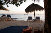 The sky begins to darken at a resort beach with a beach chair and palm tree visible