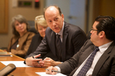 Four businesspeople sit beside each other on one side of a long desk