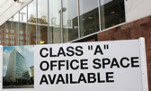 A commercial building in the background with a sign in front saying class A office space available