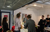 A group of people stand in a room semi-formally and have a talk