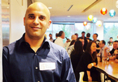 A person with a blue work t-shirt smiles toward the camera